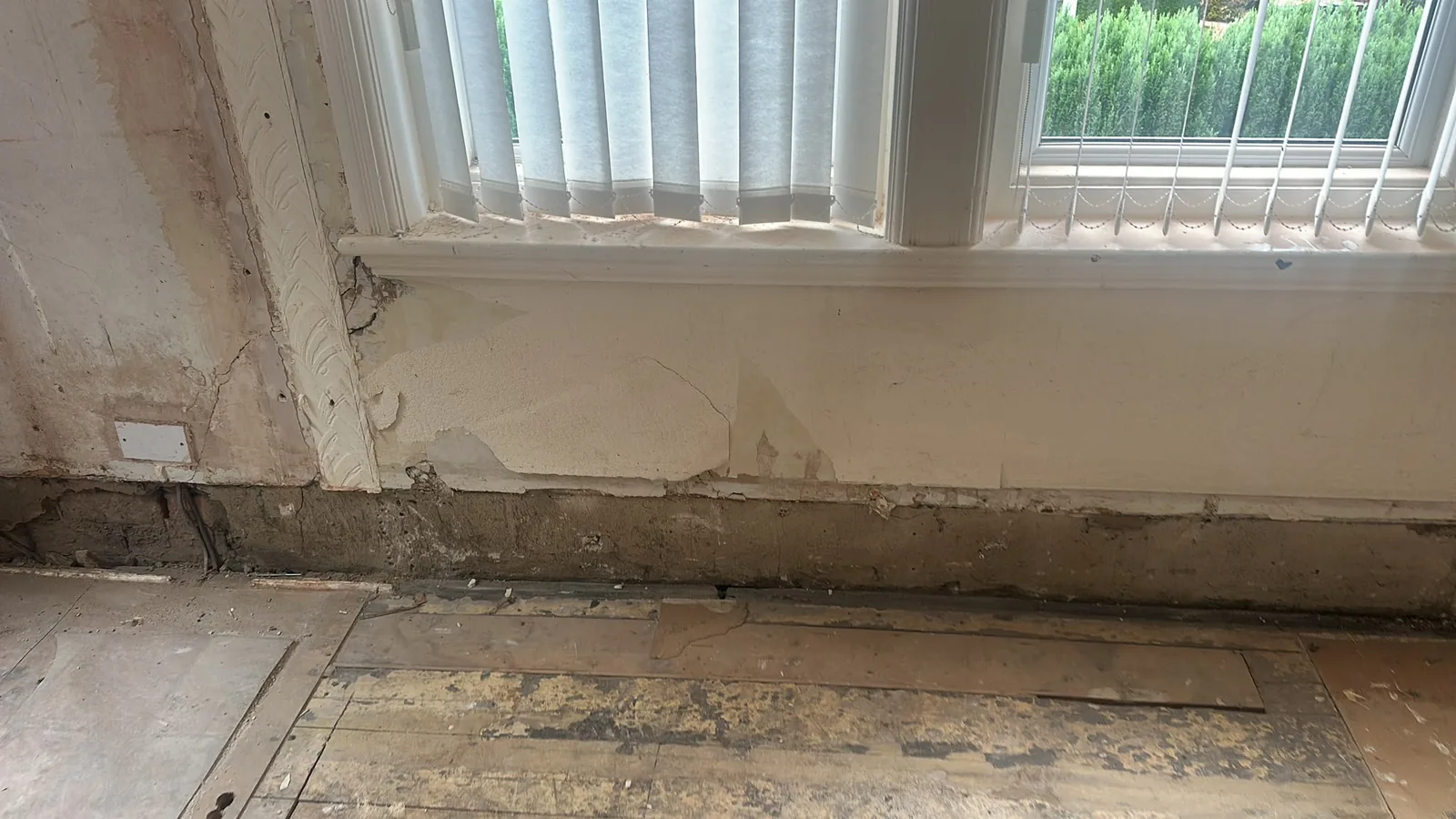 Wall beneath a residential window stripped back during refurbishment preparation